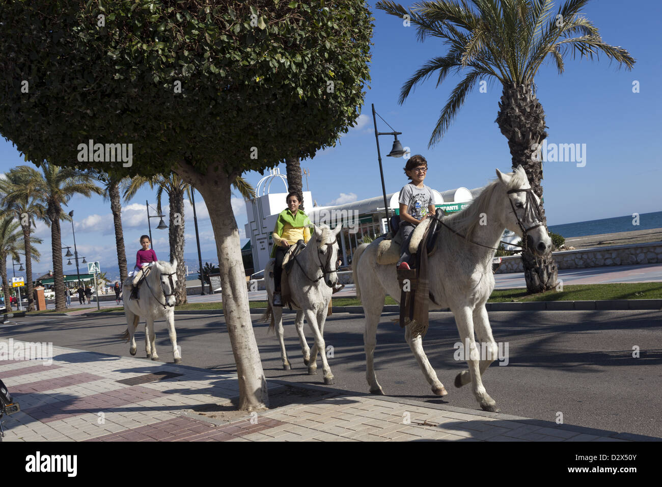 Les enfants de l'équitation le long street à Torremolinos Costa del Sol Espagne du Sud Banque D'Images