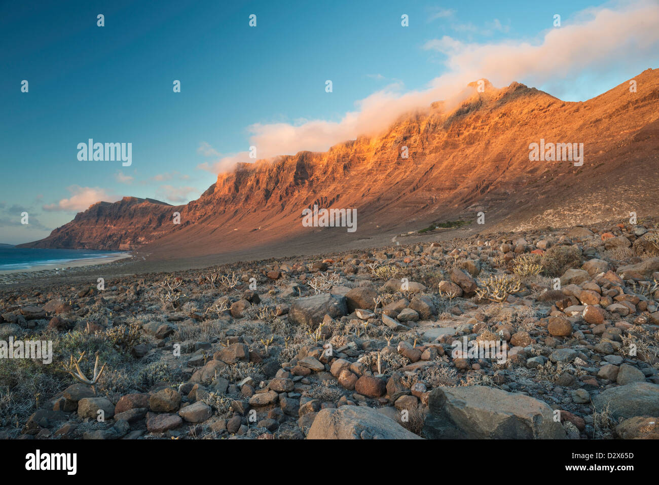 Malpais (terrain accidenté ou avec badlands gommage à sec) en face de la falaise de Famara et plage de Caleta de Famara, Lanzarote Banque D'Images