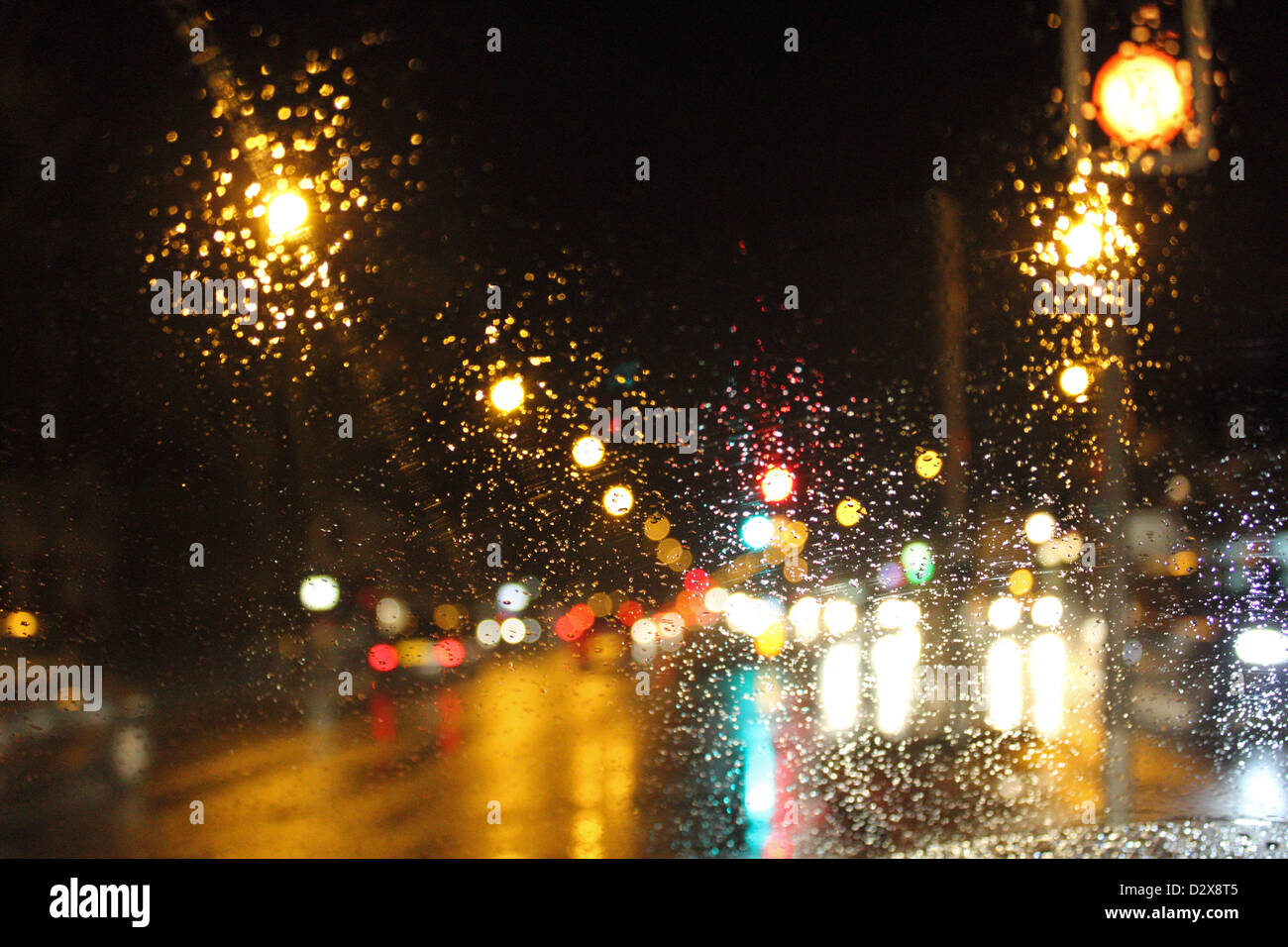 Rue et de voiture à travers les gouttes de pluie sur les pare-brise de voiture dans la nuit. England UK Banque D'Images