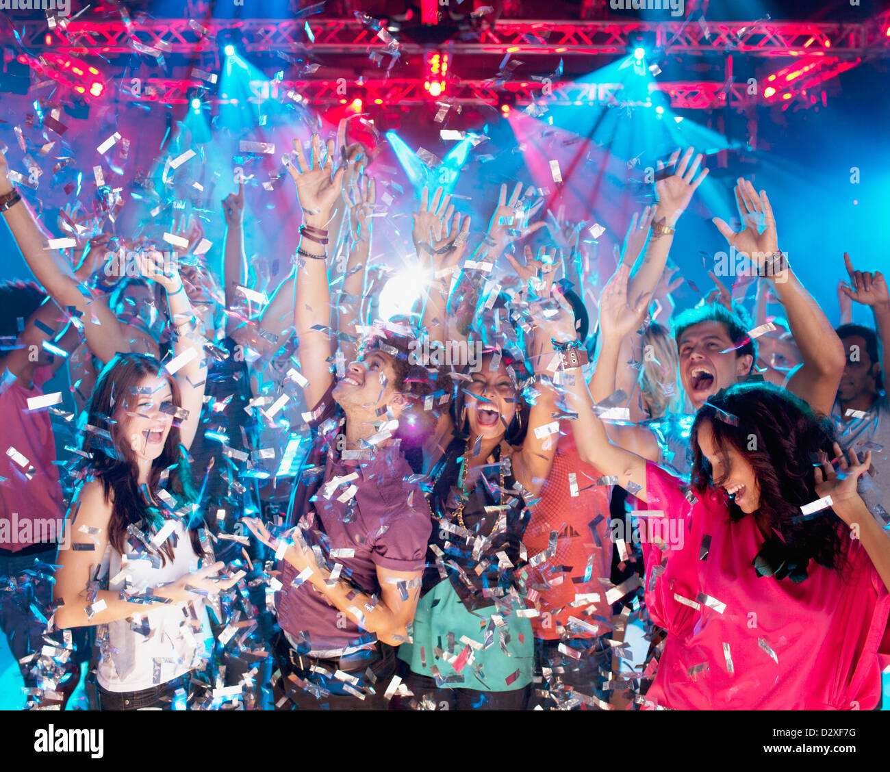Confettis tombent sur la foule enthousiaste de danse de discothèque Banque D'Images