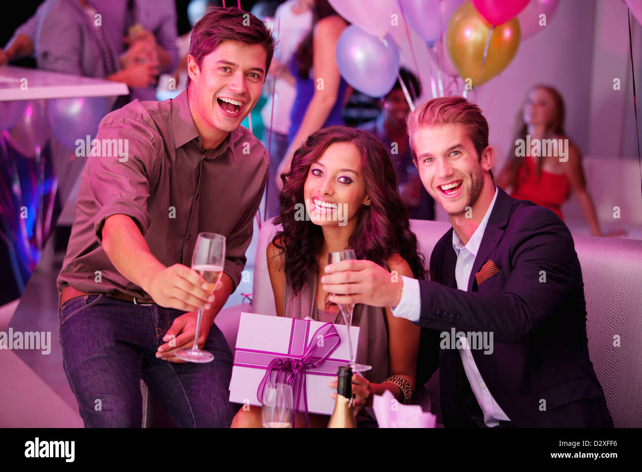 Portrait d'amis enthousiastes avec champagne et cadeau Banque D'Images