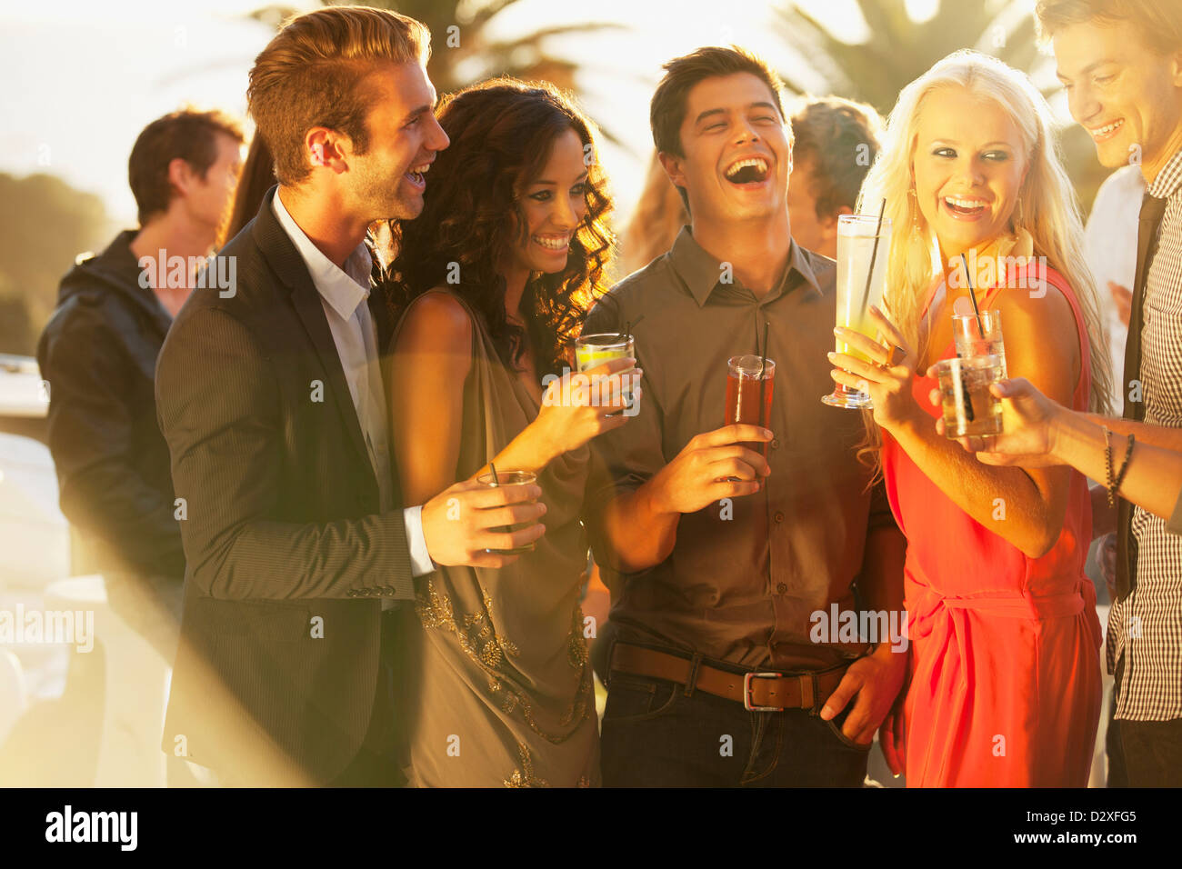 Laughing friends drinking cocktails sur balcon ensoleillé Banque D'Images