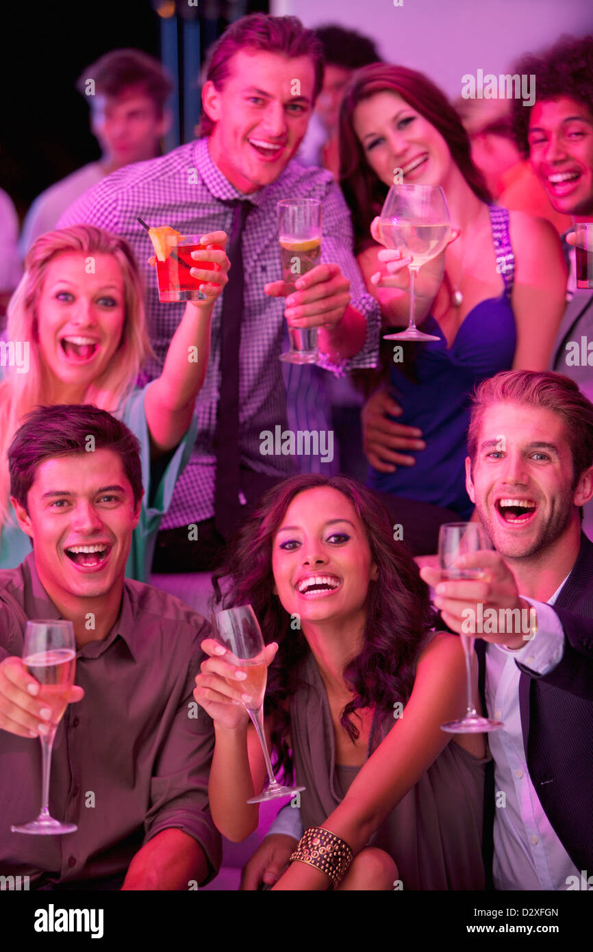 Portrait of smiling friends drinking cocktails in nightclub Banque D'Images