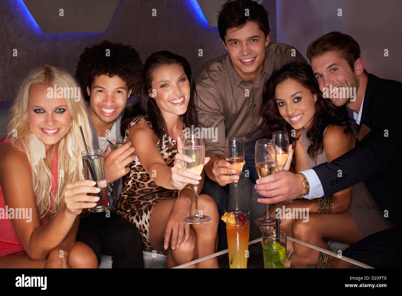 Portrait of smiling friends toasting cocktails in nightclub Banque D'Images
