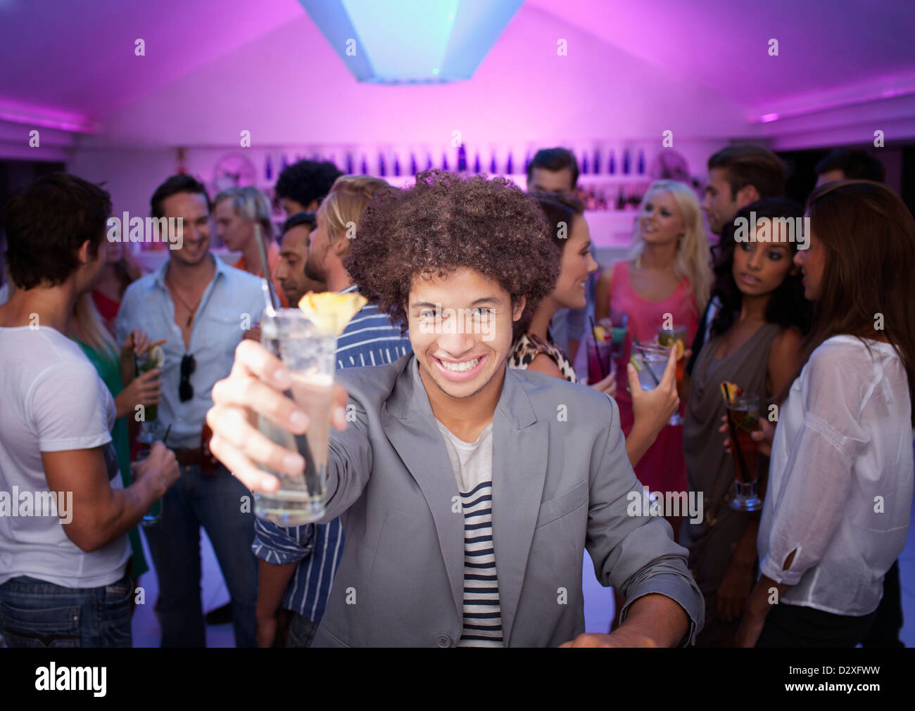 Portrait of smiling man holding cocktail au bar in nightclub Banque D'Images