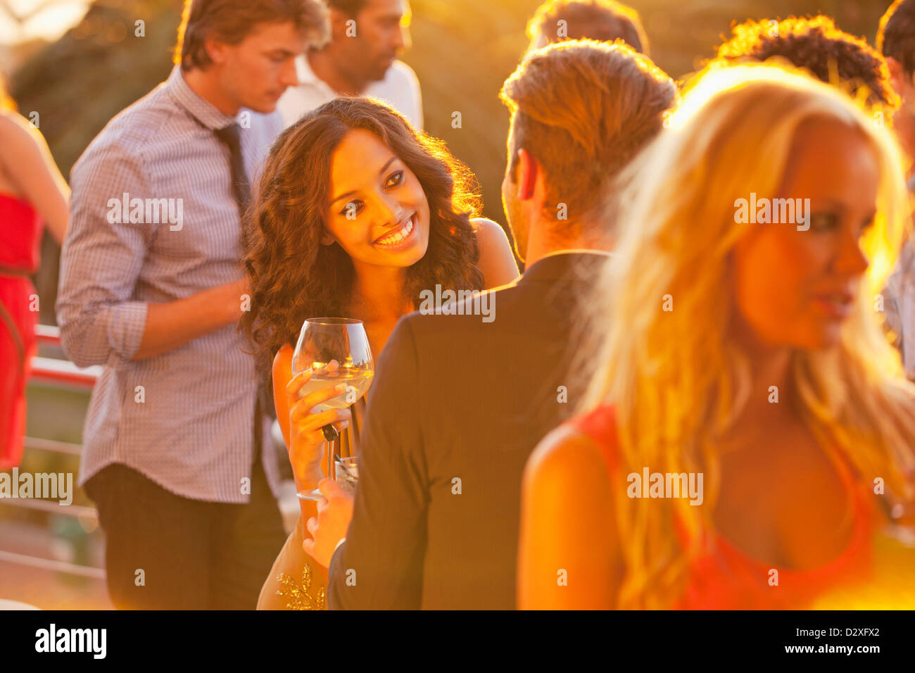 Femme souriante avec un verre de vin à parler à l'homme sur le balcon ensoleillé Banque D'Images