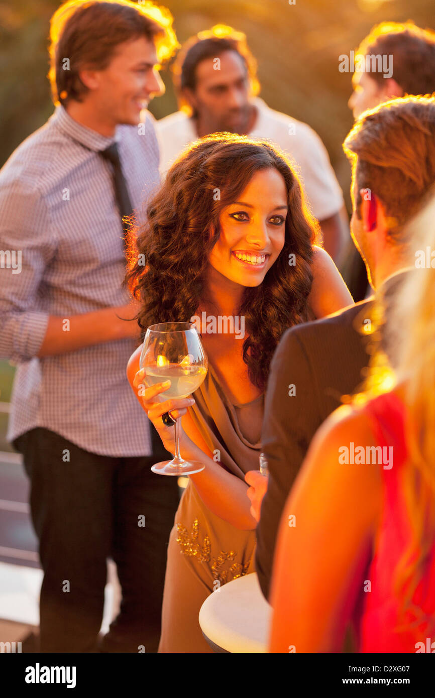 Femme souriante avec un verre de vin à parler à l'homme sur le balcon ensoleillé Banque D'Images