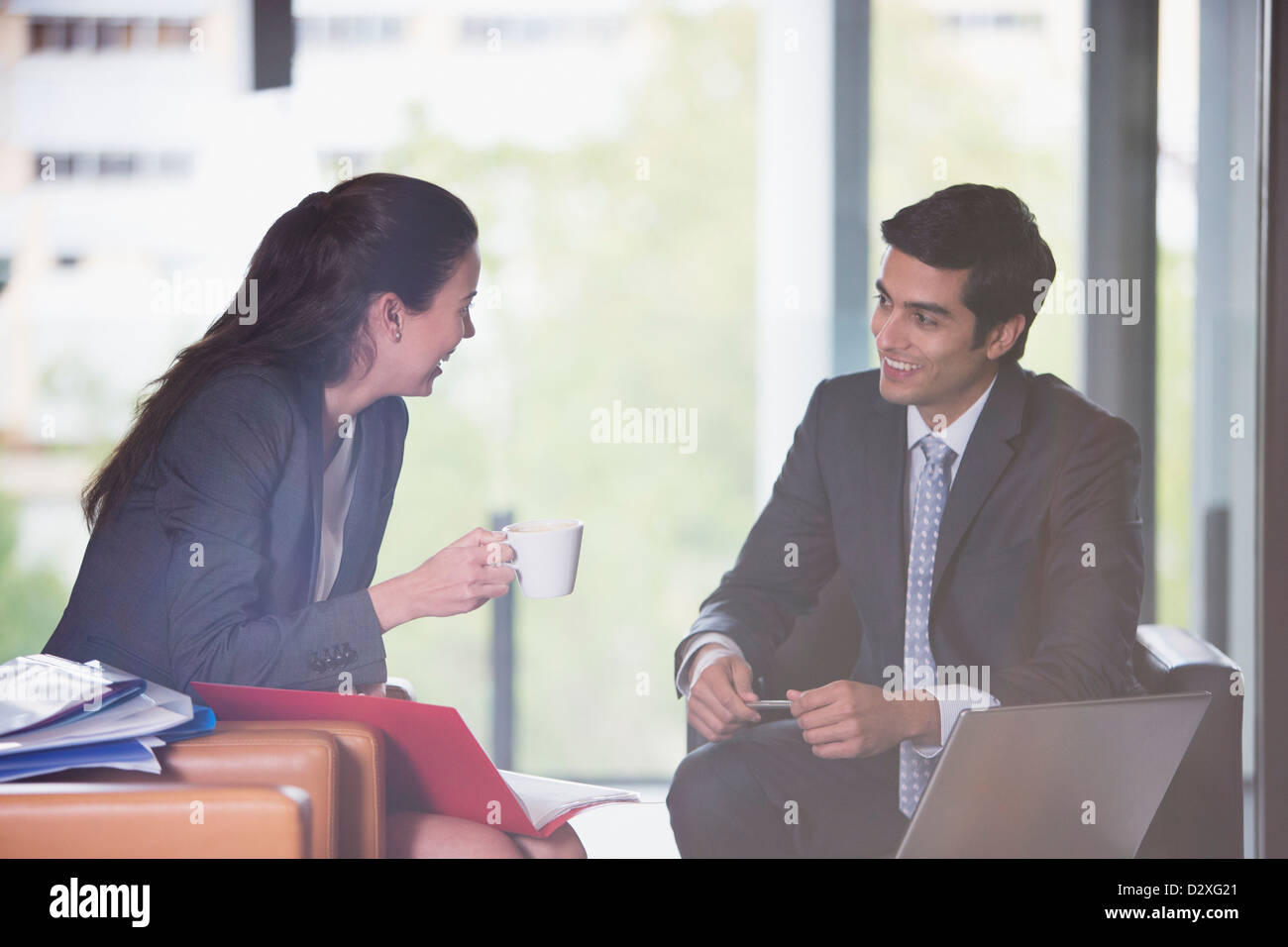 Smiling businessman and businesswoman avec café, ordinateur portable et de la paperasserie Banque D'Images