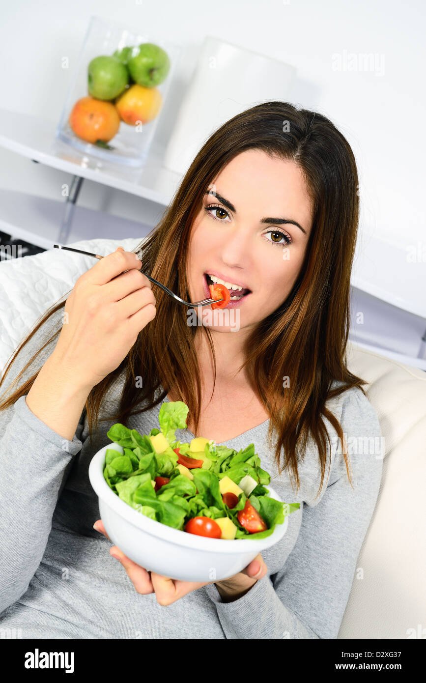 Jeune femme séduisante est de manger une salade fraîche à la maison Banque D'Images