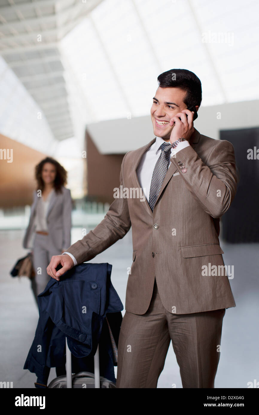 Smiling businessman talking on cell phone at airport Banque D'Images