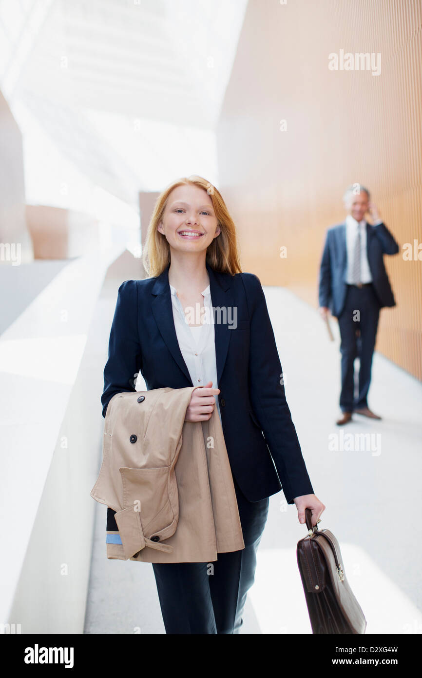 Portrait of smiling businesswoman avec manteau et porte-documents Banque D'Images
