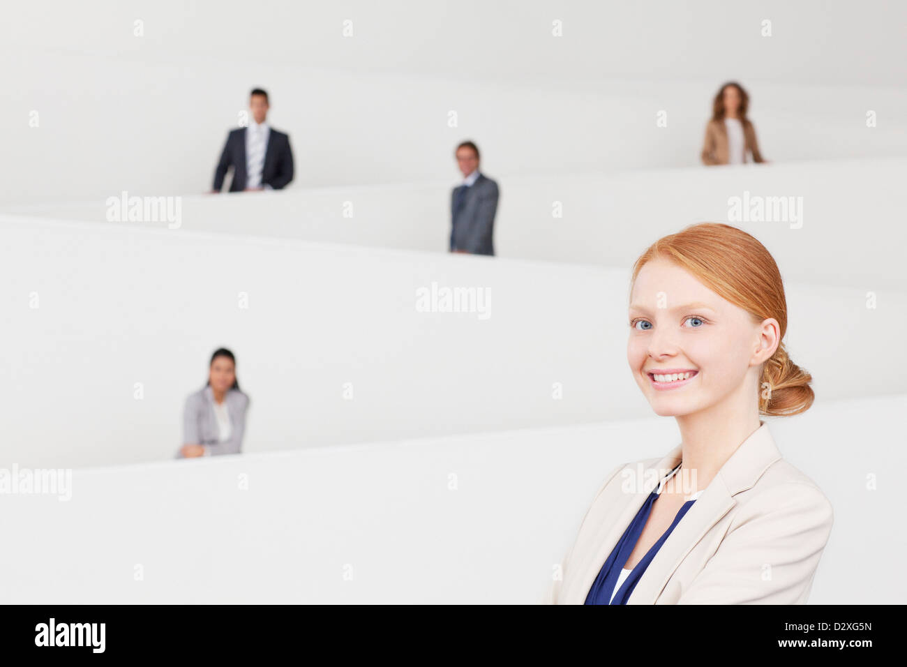 Portrait of smiling businesswoman with co-workers on staircase en arrière-plan Banque D'Images