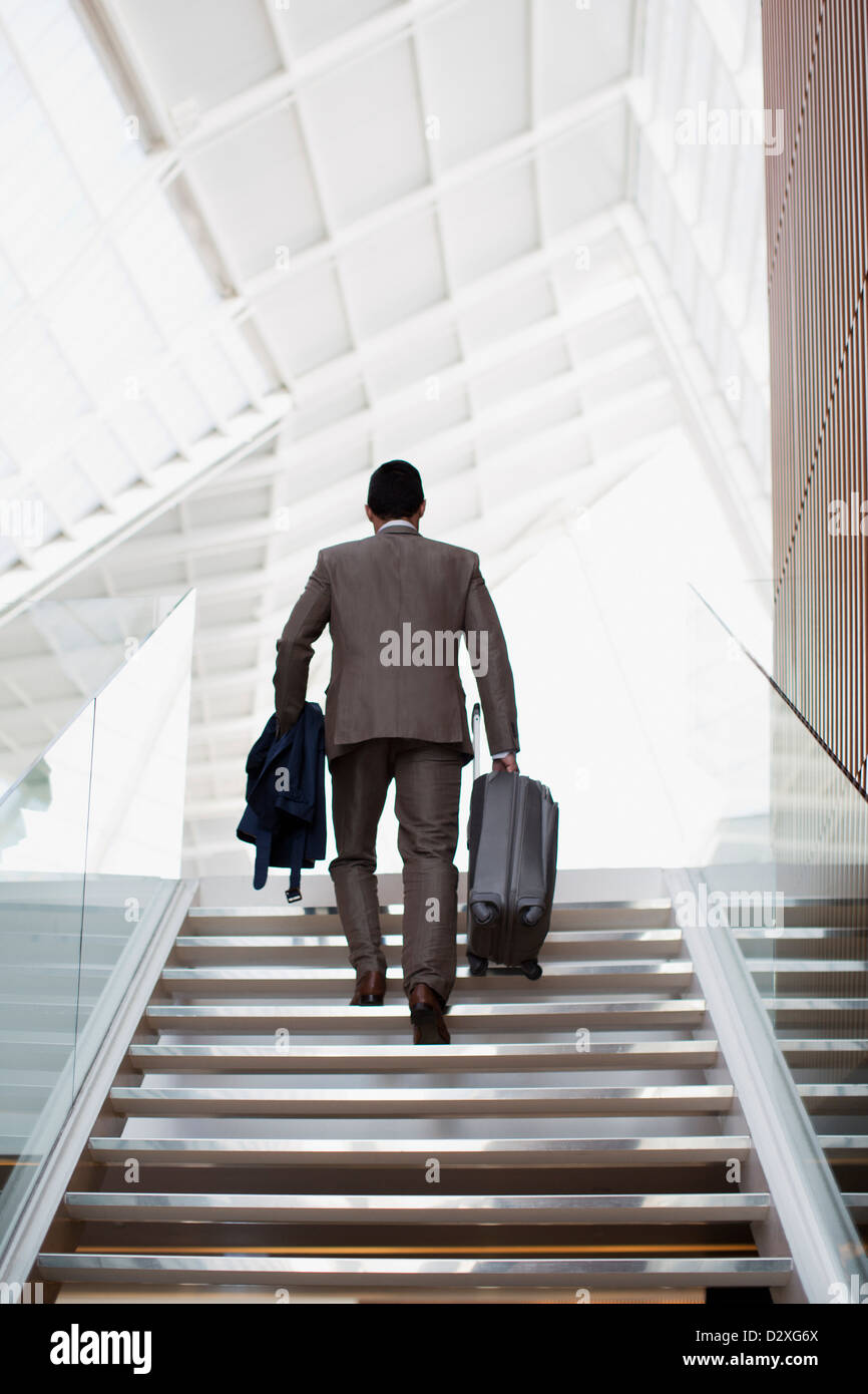 Businessman with suitcase ascending stairs Banque D'Images