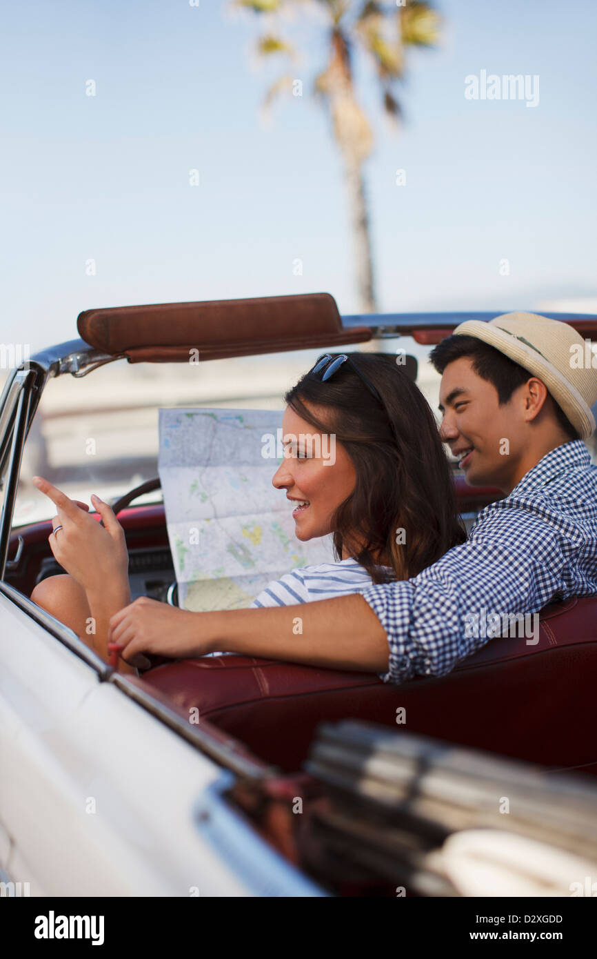 Smiling couple reading road map convertible Banque D'Images