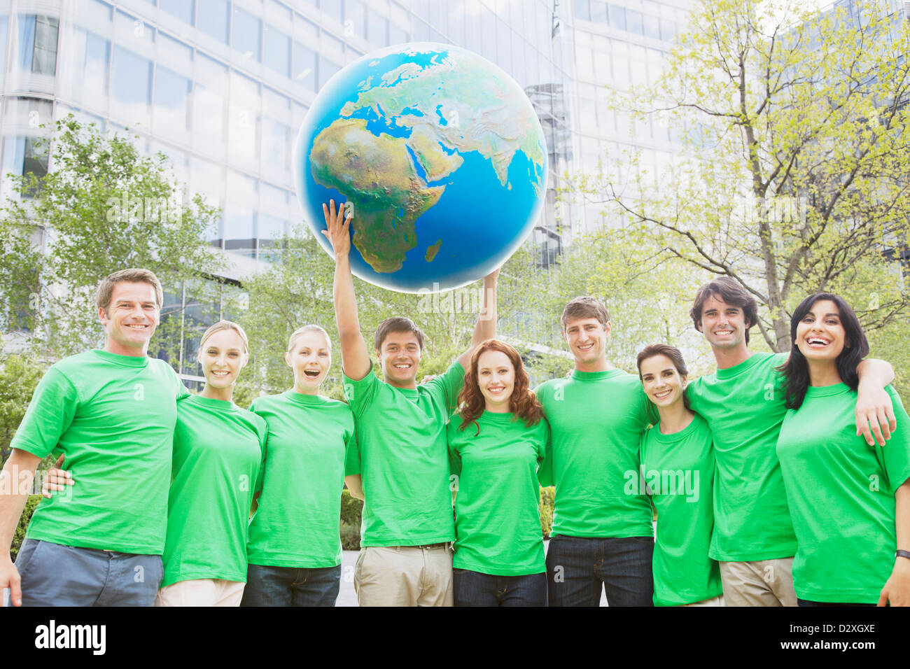Portrait de l'équipe en vert t-shirts lifting globe frais généraux Banque D'Images