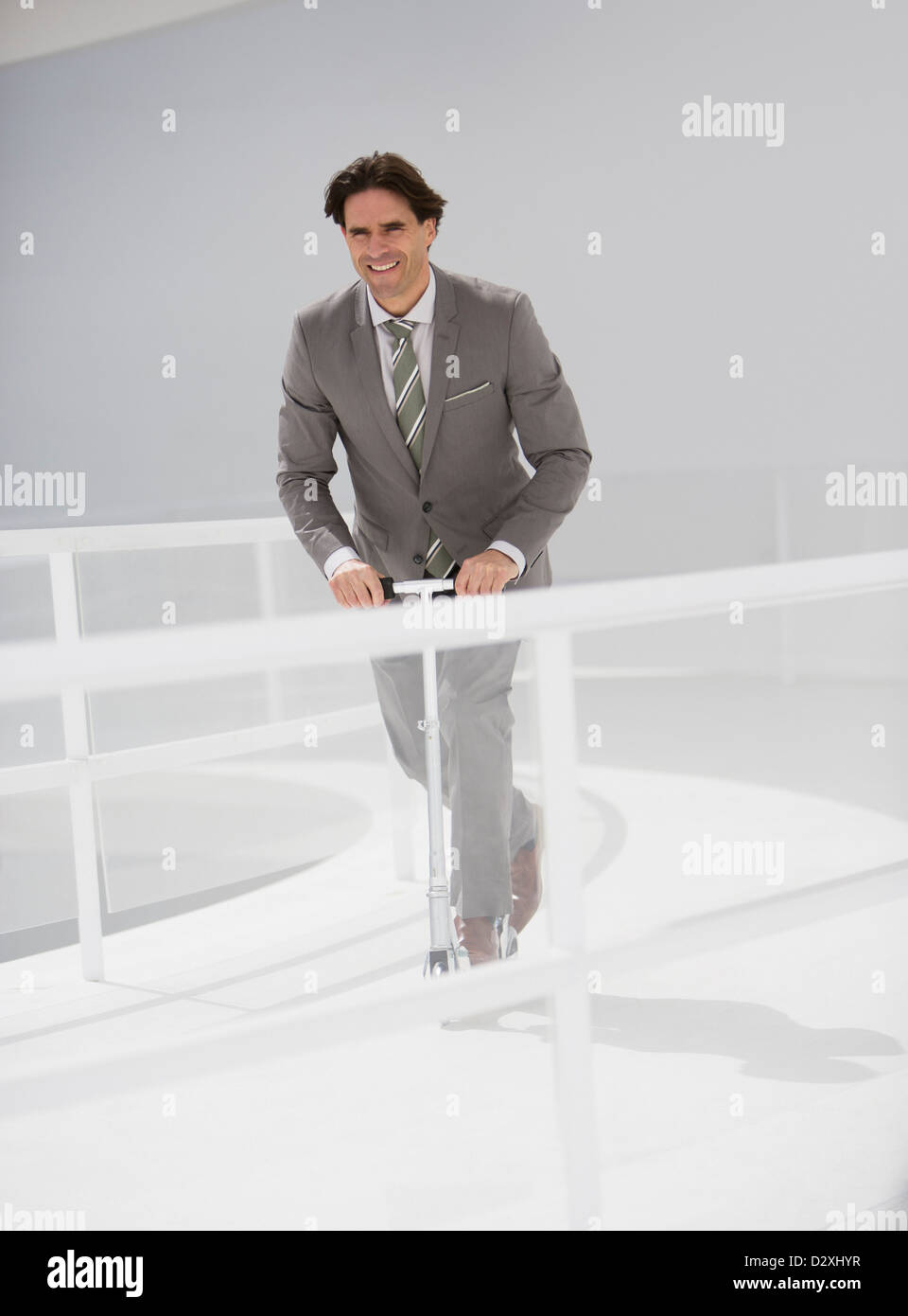 Smiling businessman riding scooter le long chemin de ronde Banque D'Images