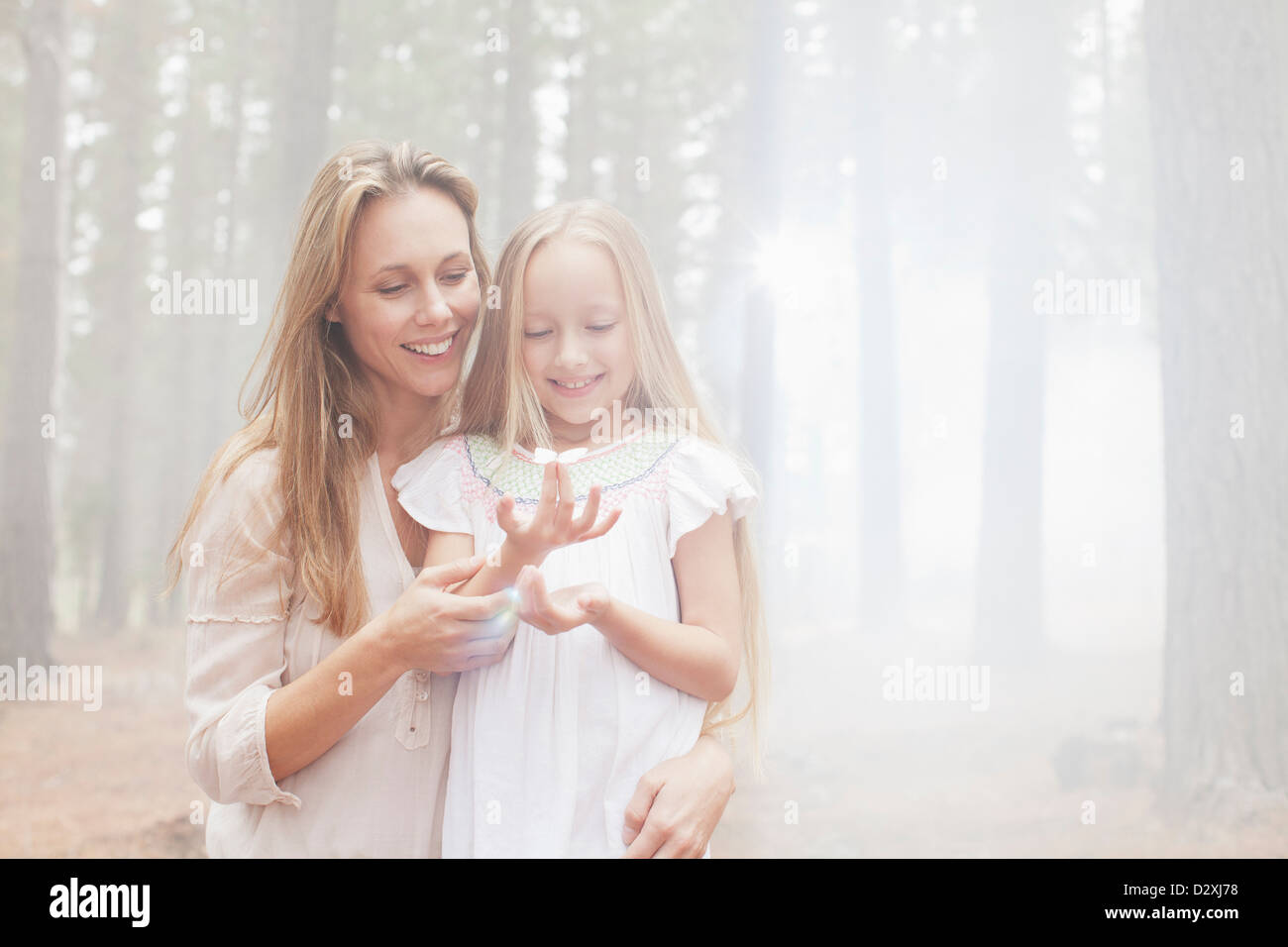 Smiling mother and daughter in sunny woods Banque D'Images