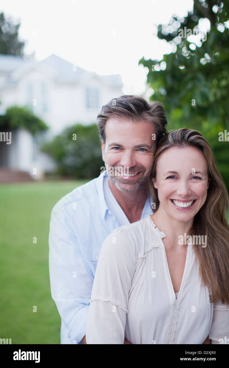 Portrait of smiling couple dans une cour avec la maison en arrière-plan Banque D'Images Portrait of smiling couple dans une cour avec la maison en arrière-plan Banque D'Images