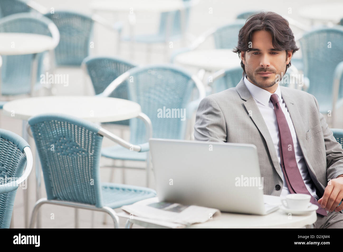 Businessman using laptop at sidewalk cafe Banque D'Images