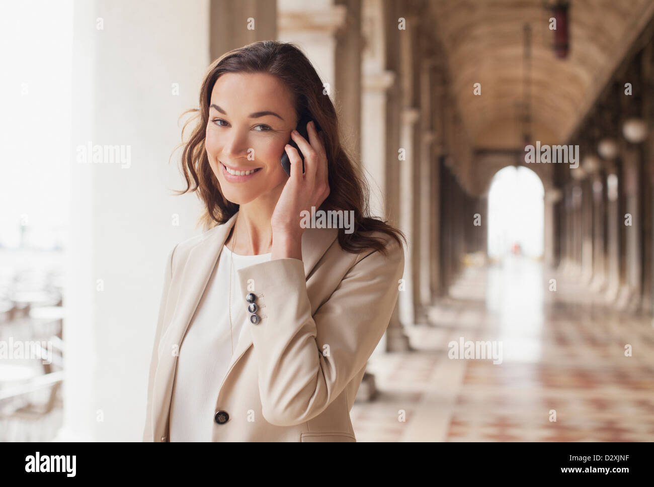 Portrait of smiling businesswoman talking on cell phone in corridor Banque D'Images