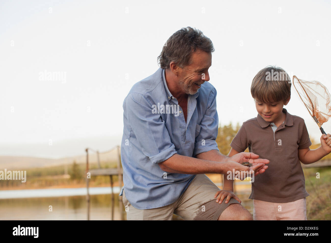 Smiling grandfather and grandson fishing at lakeside Banque D'Images