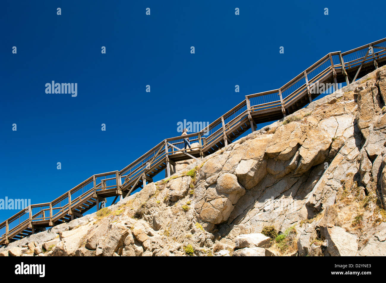 Jeune femme monte escalier raide sur une montagne avec ciel bleu derrière comme copy space Banque D'Images