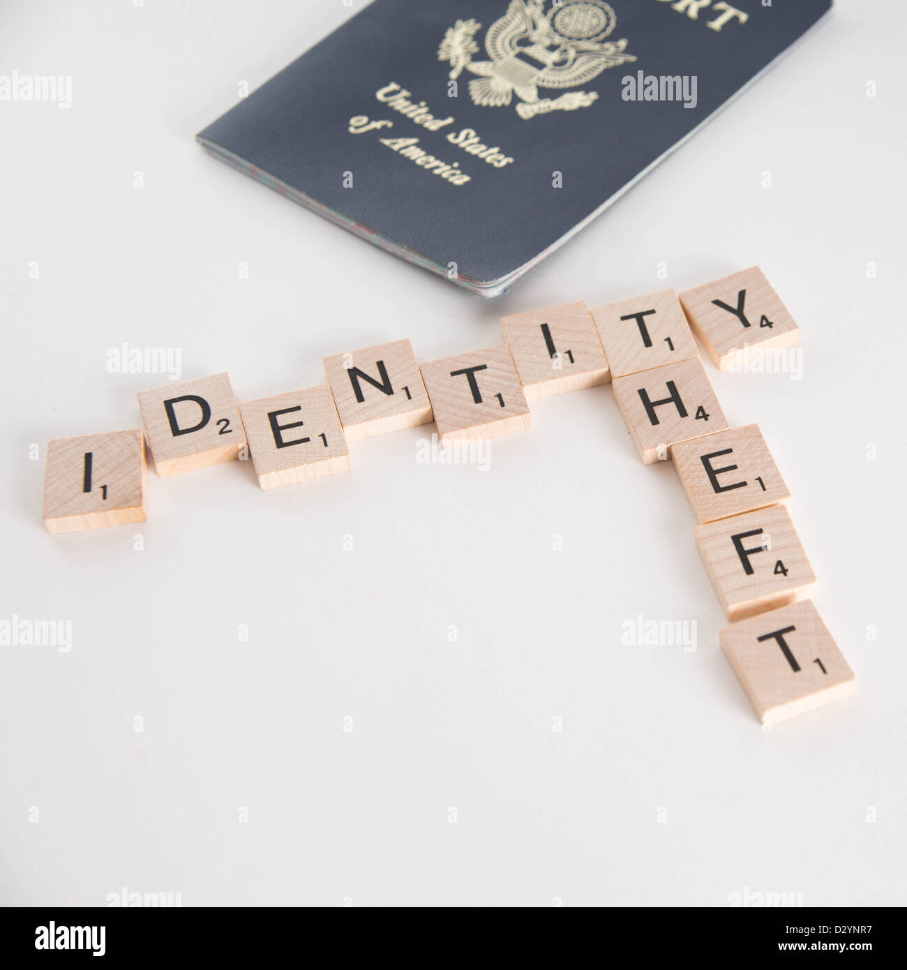 Le vol d'identité écrit en lettres de Scrabble avec nous de passeport dans  l'arrière-plan. Isolé sur fond blanc Photo Stock - Alamy
