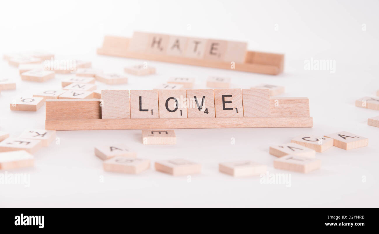 Scrabble en bois letters spelling out 'Love' et 'La haine'. "La haine" en arrière-plan de netteté. Isolé sur fond blanc. Banque D'Images