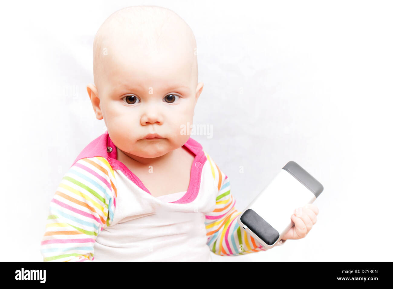 Petit bébé dans des vêtements à rayures occasionnels est titulaire d'un téléphone portable Banque D'Images