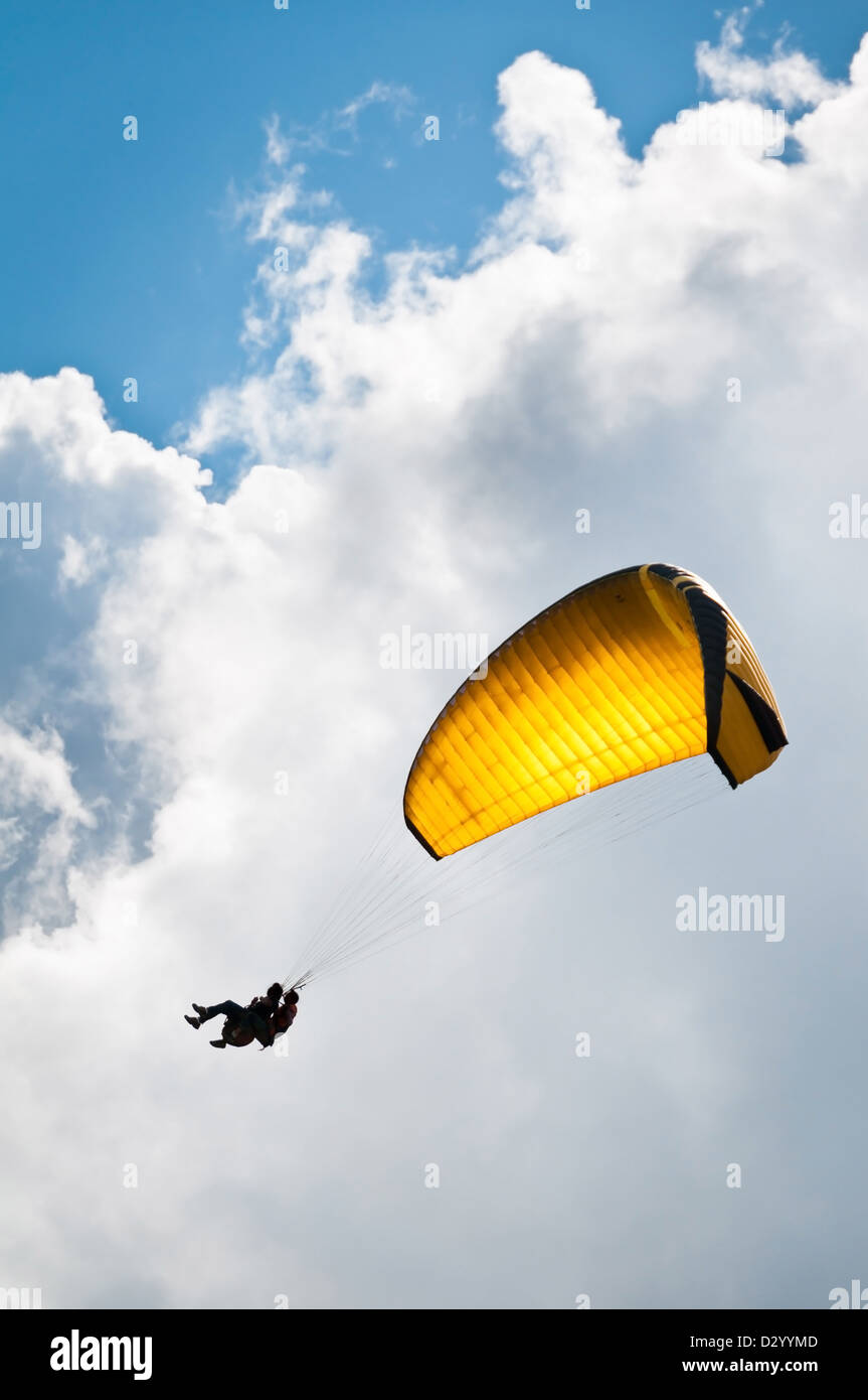 Parachuter avec moniteur en ordre décroissant d'un parachute jaune contre Ciel et nuages Banque D'Images