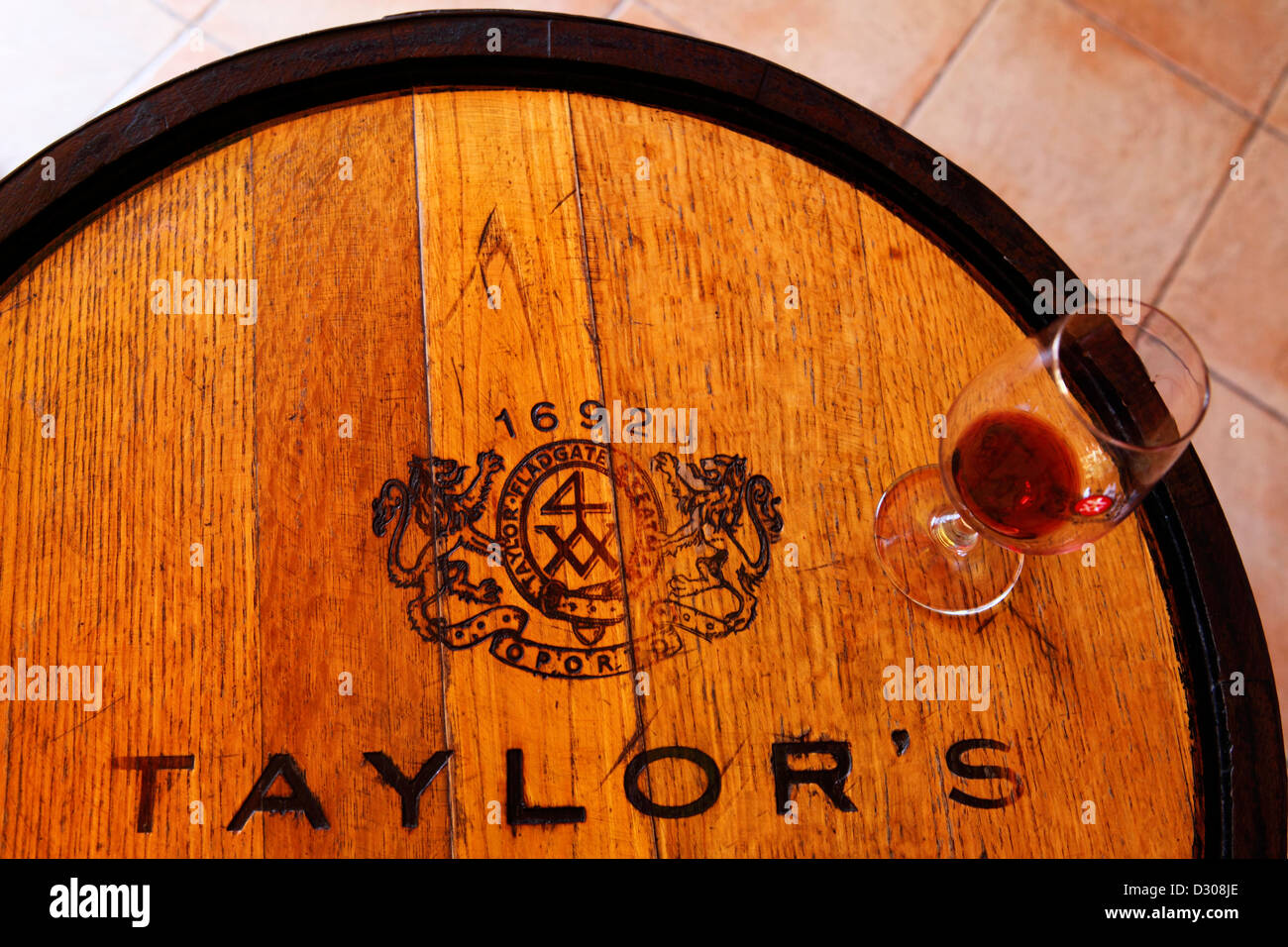 Verre de vin se dresse sur un baril de Taylor lors d'une dégustation de vin de Porto à Vila Nova de Gaia, Portugal. Banque D'Images