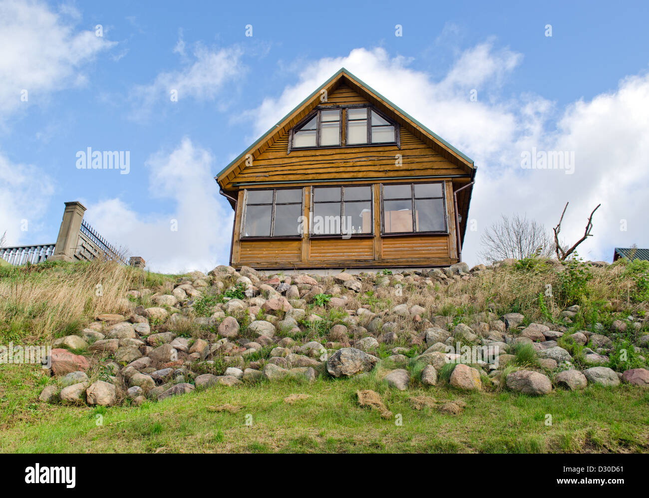 Homestead en bois construction de maisons rurales sur petite colline couverte de pierres de roche sur fond bleu ciel nuageux. Banque D'Images