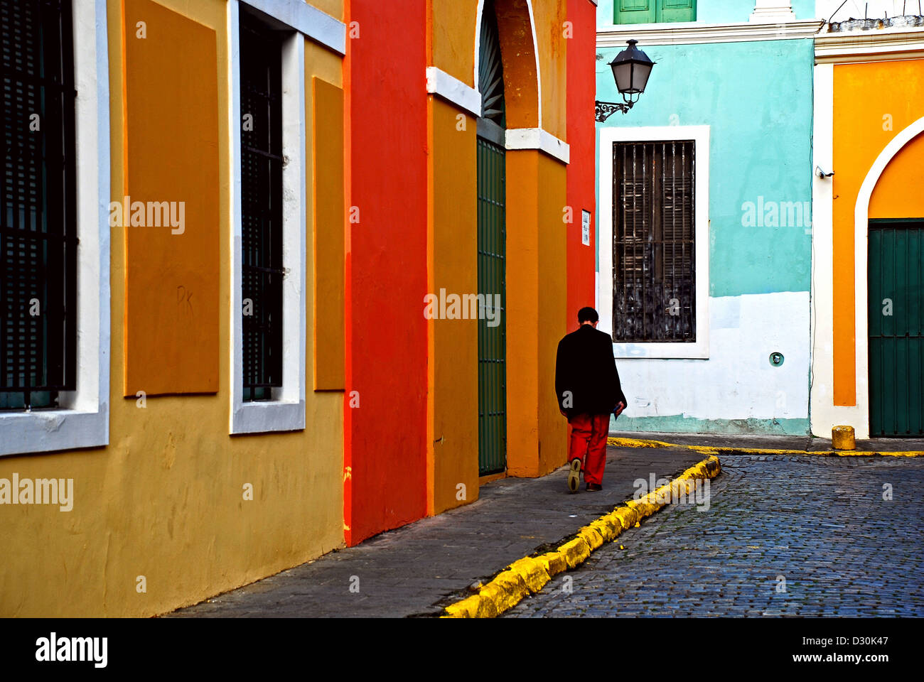 Un homme avec un pantalon rouge, marche le rues colorées du vieux San Juan, Puerto Rico. Banque D'Images