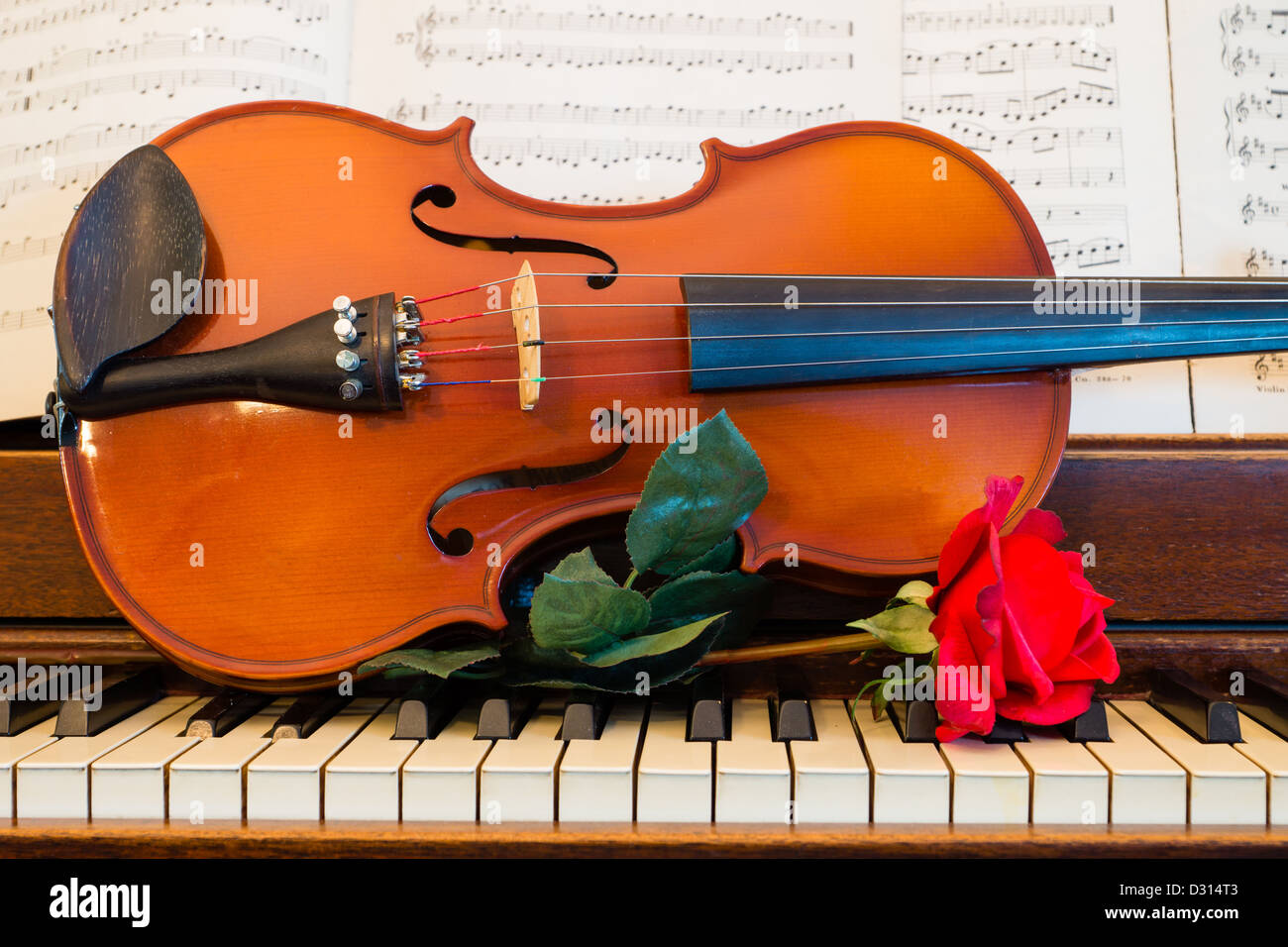 Une rose, violon, partitions et s'asseoir sur un piano en préparation pour une nuit de musique. Banque D'Images