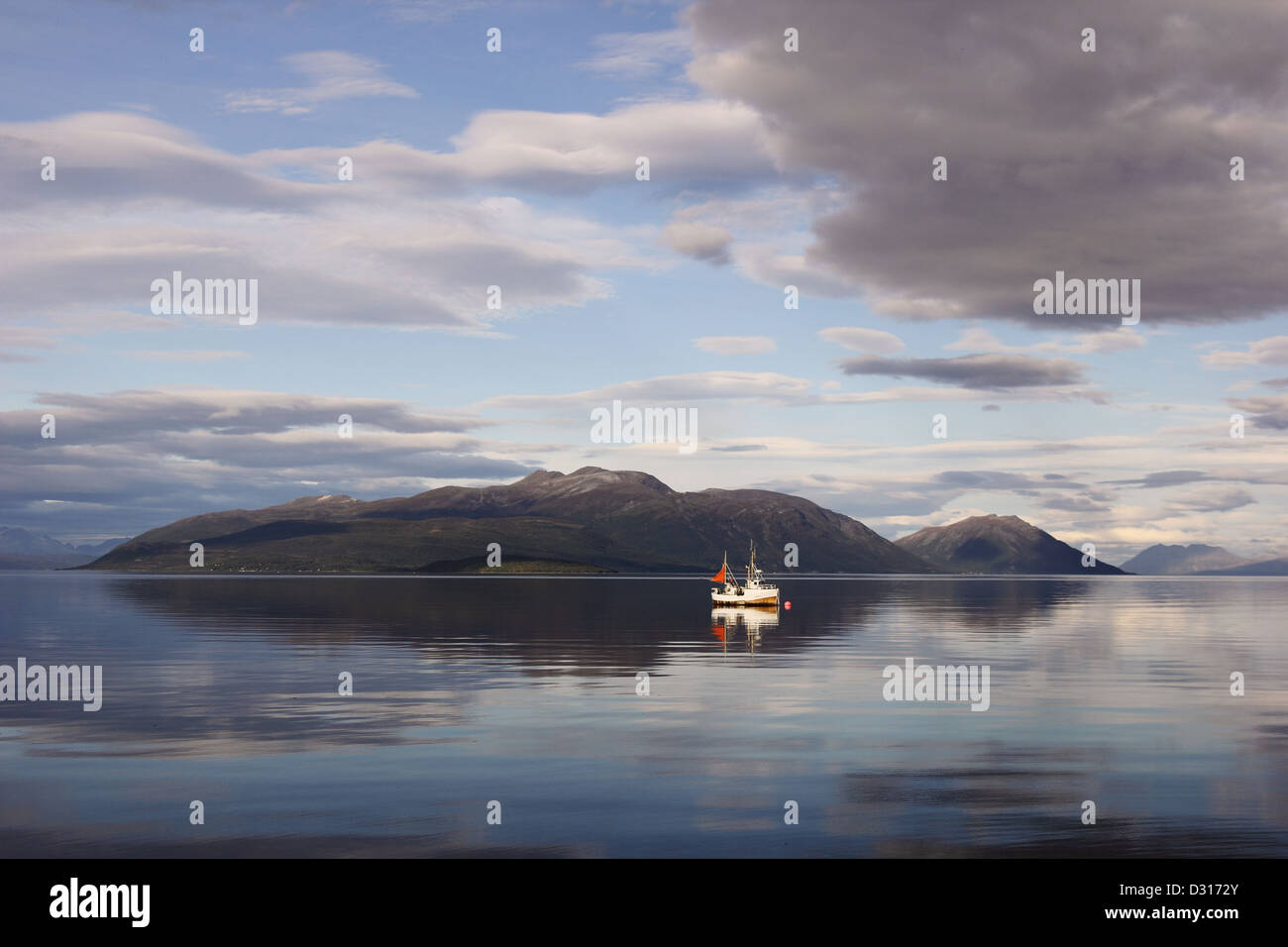 Scène tranquille dans les fjords norvégiens du nord - un seul bateau de pêche dans les eaux calmes. Banque D'Images