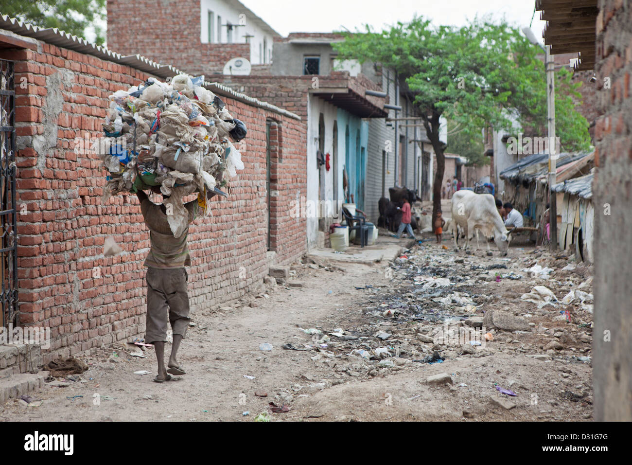 La pauvreté vivant dans Tehkhand Slum, Delhi, Inde. Un homme porte une grande charge de déchets récupérés sur sa tête. Banque D'Images