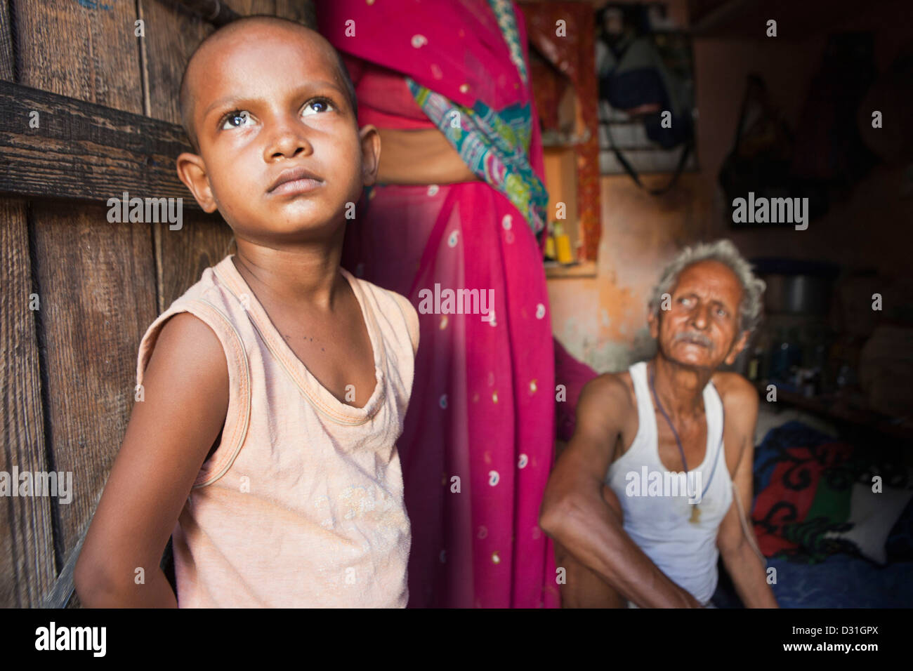 Jeune Indien enfant se tient à la porte de sa maison à Tehkhand Slum, Delhi, Inde. 8 membres de la famille vivent ici. Banque D'Images