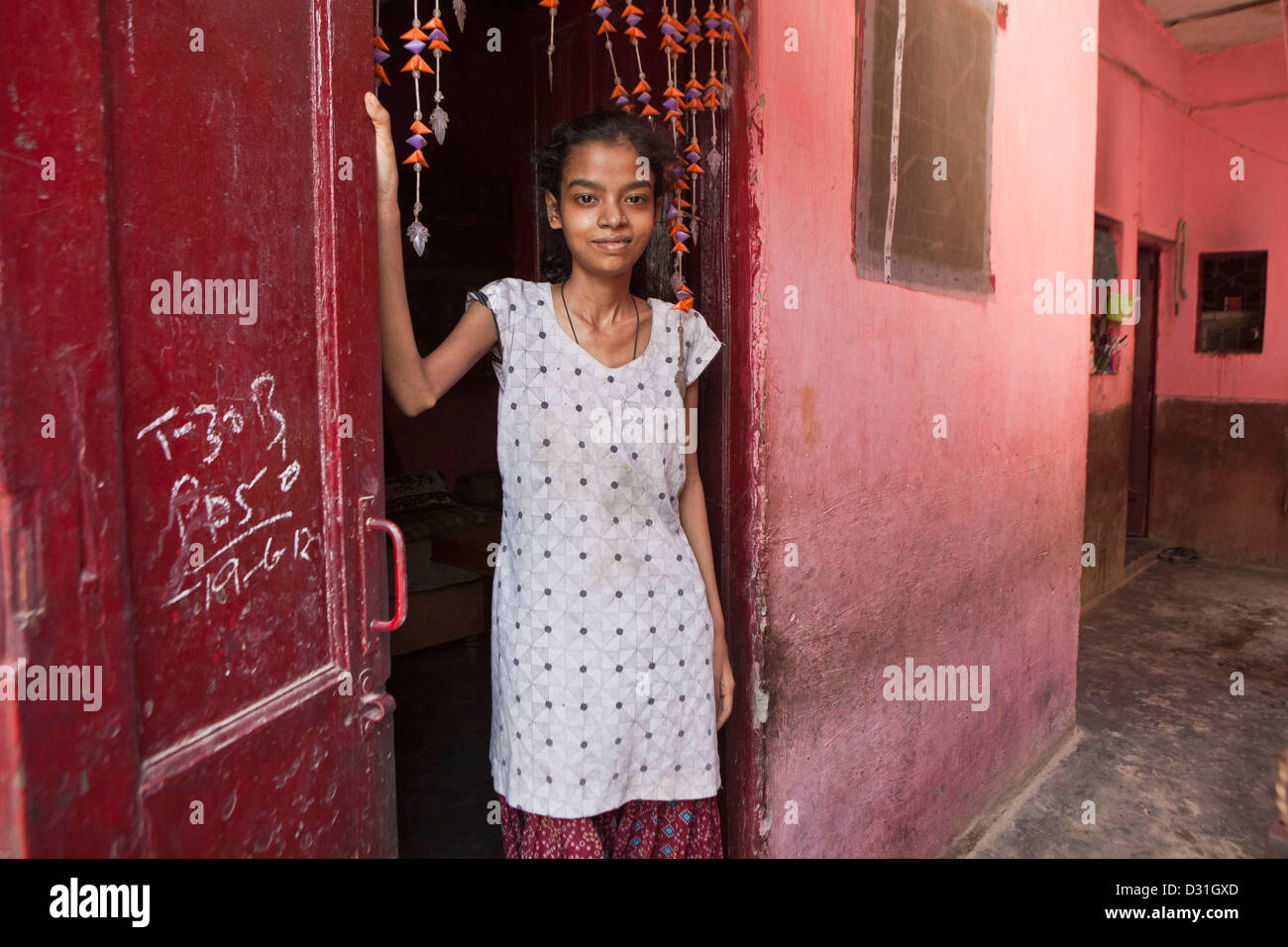 Une jeune femme indienne se tient à la porte de sa maison en Meethapur slum, Delhi, Inde. Banque D'Images