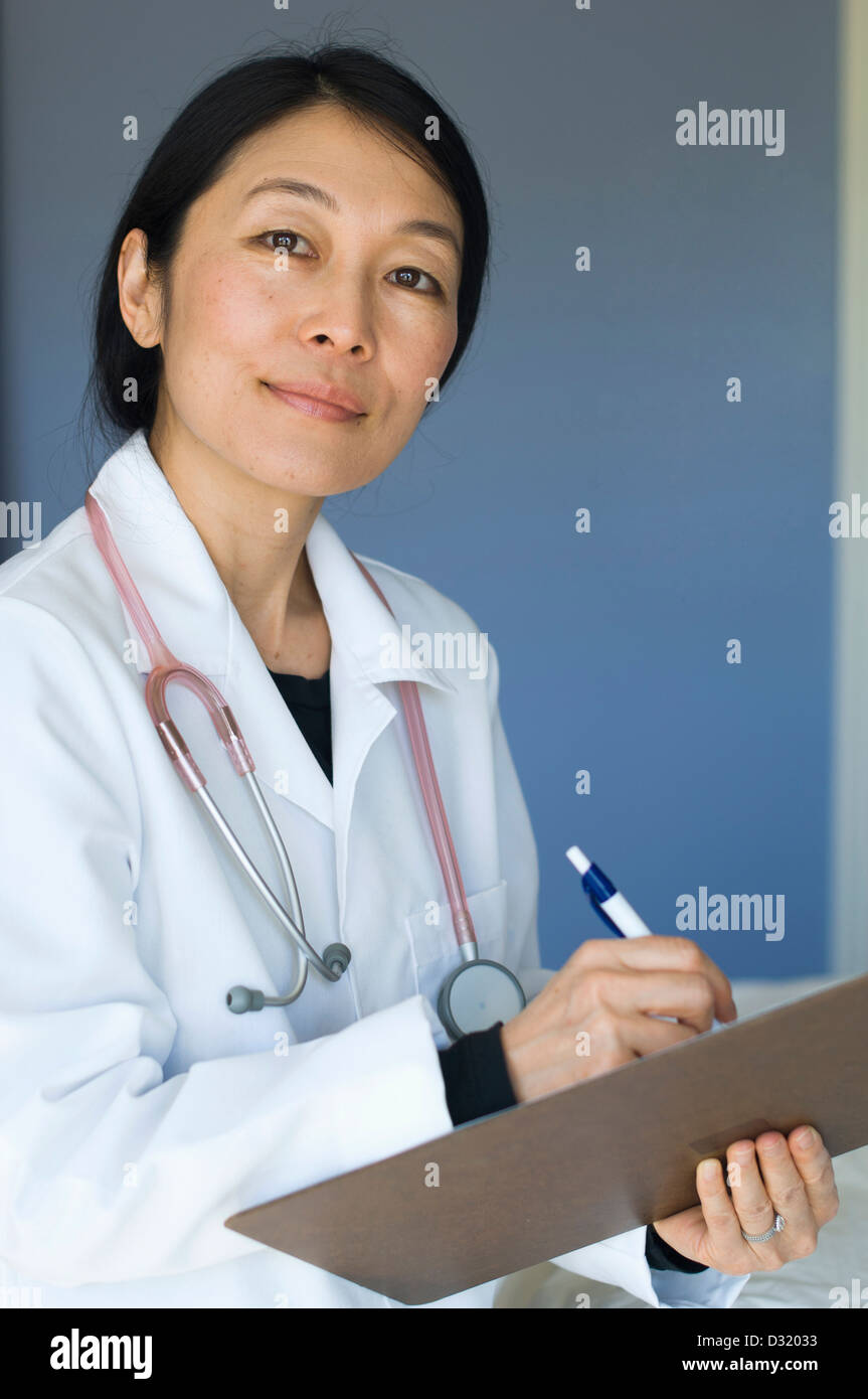 Médecin japonais writing on clipboard Banque D'Images