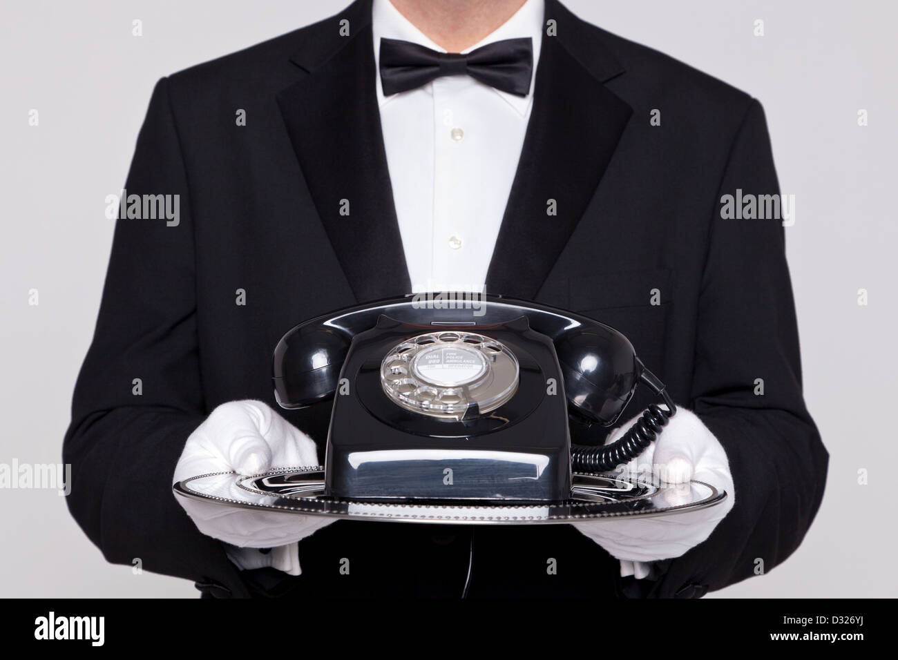 Butler holding a silver tray avec un vieux téléphone retro noir sur elle. Banque D'Images
