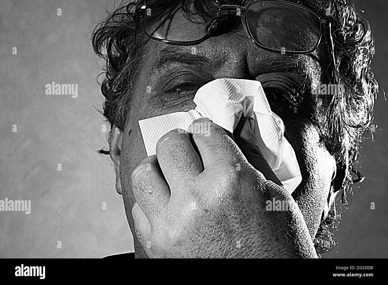 Homme d'âge moyen soufflant son nez dans un mouchoir, noir et blanc Banque D'Images