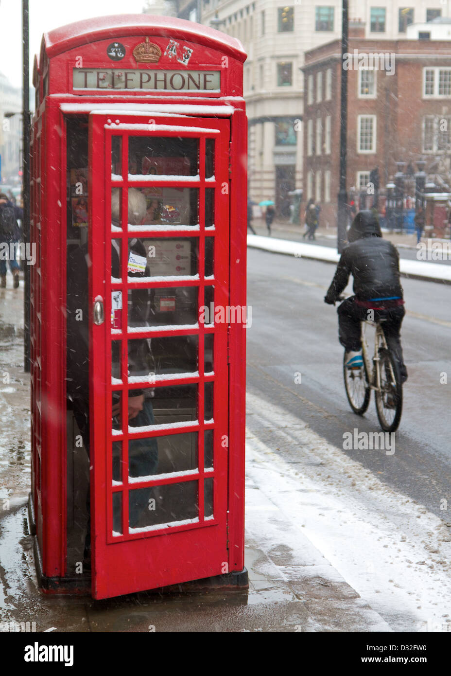 Boîte de téléphone et de cyclistes dans la neige sur Piccadilly, Londres Banque D'Images