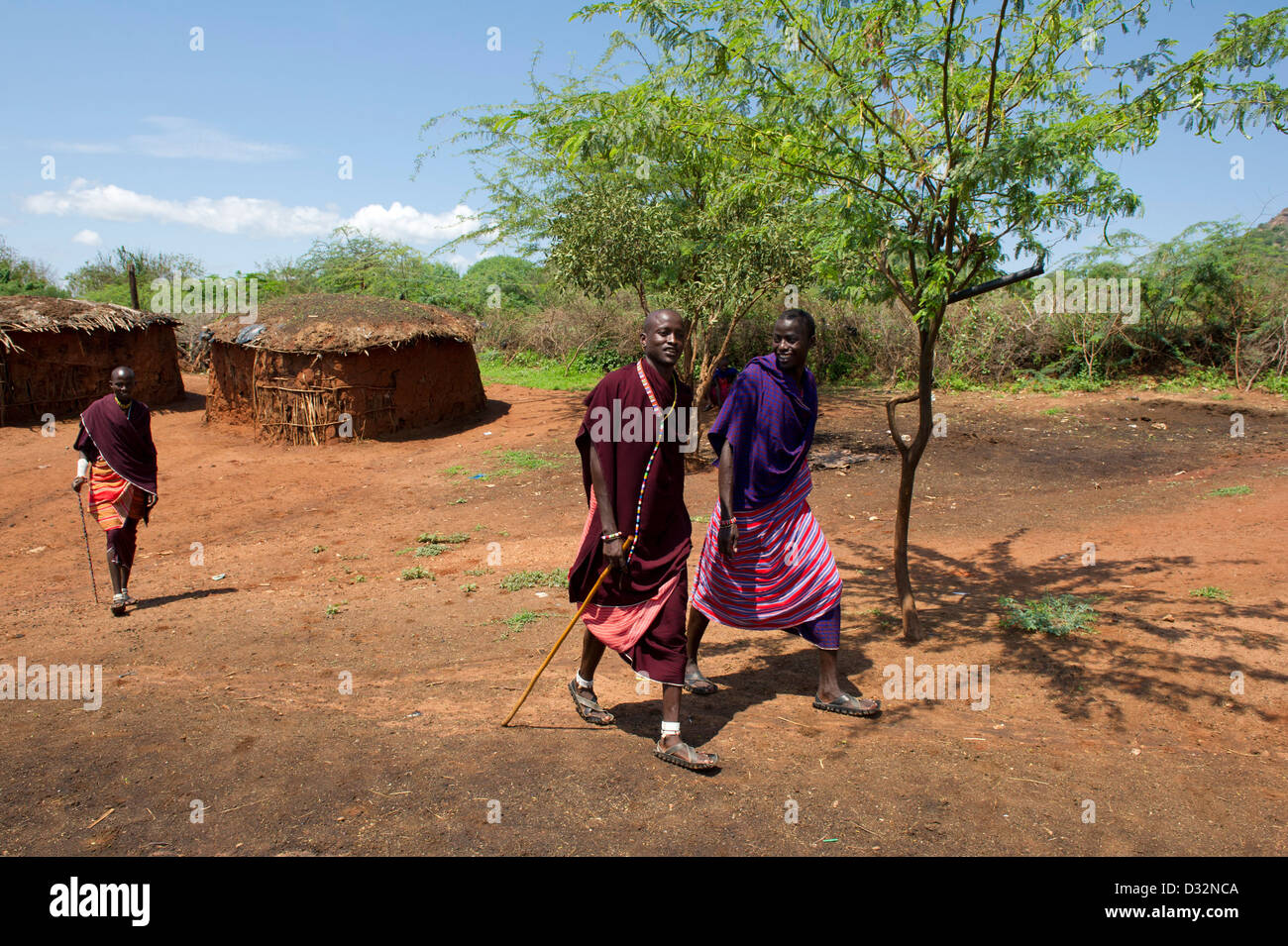 Les hommes Masaï et huttes traditionnelles dans le manyatta, Kenya Banque D'Images