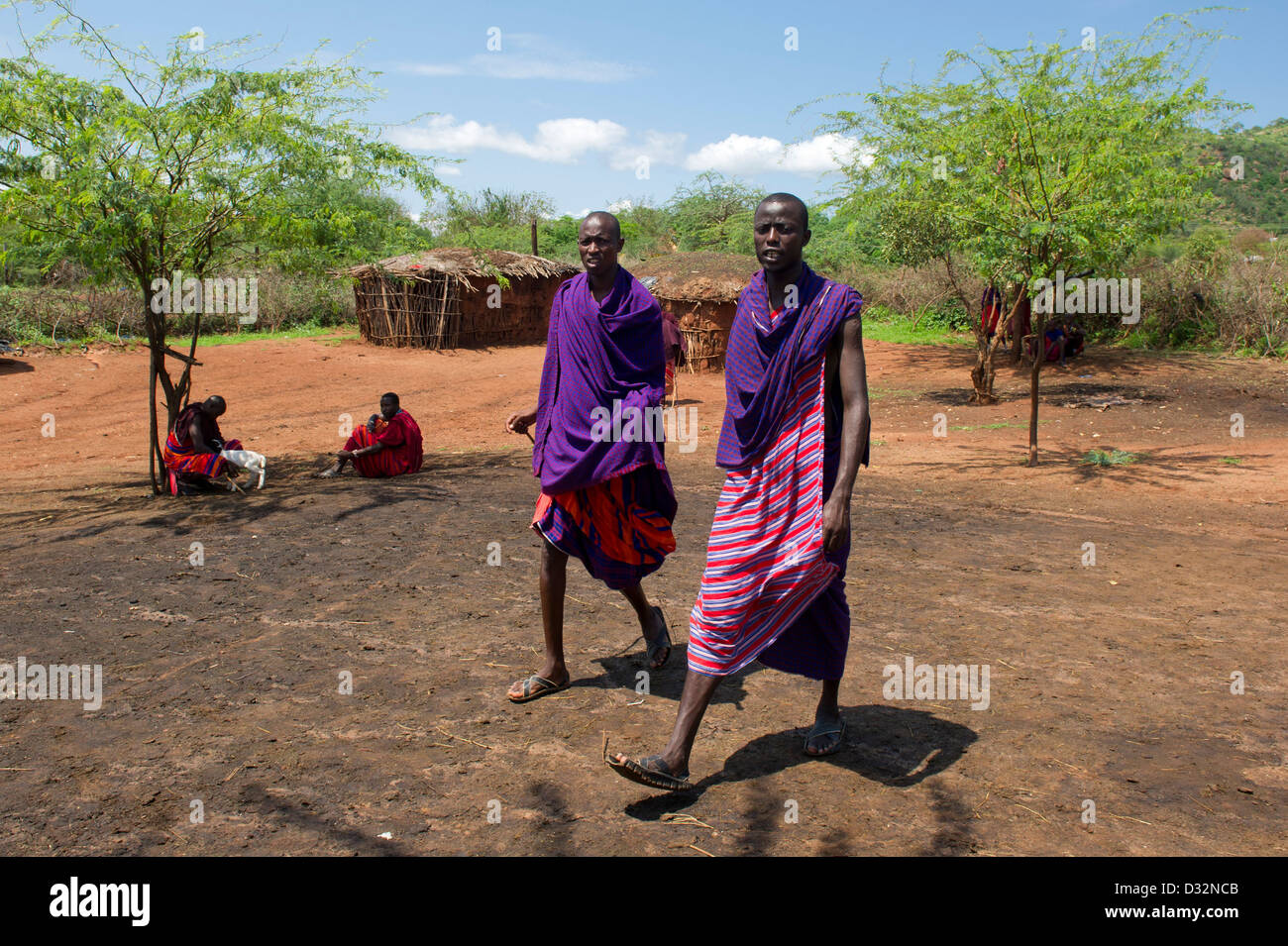 Les hommes Masaï et huttes traditionnelles dans le manyatta, Kenya Banque D'Images