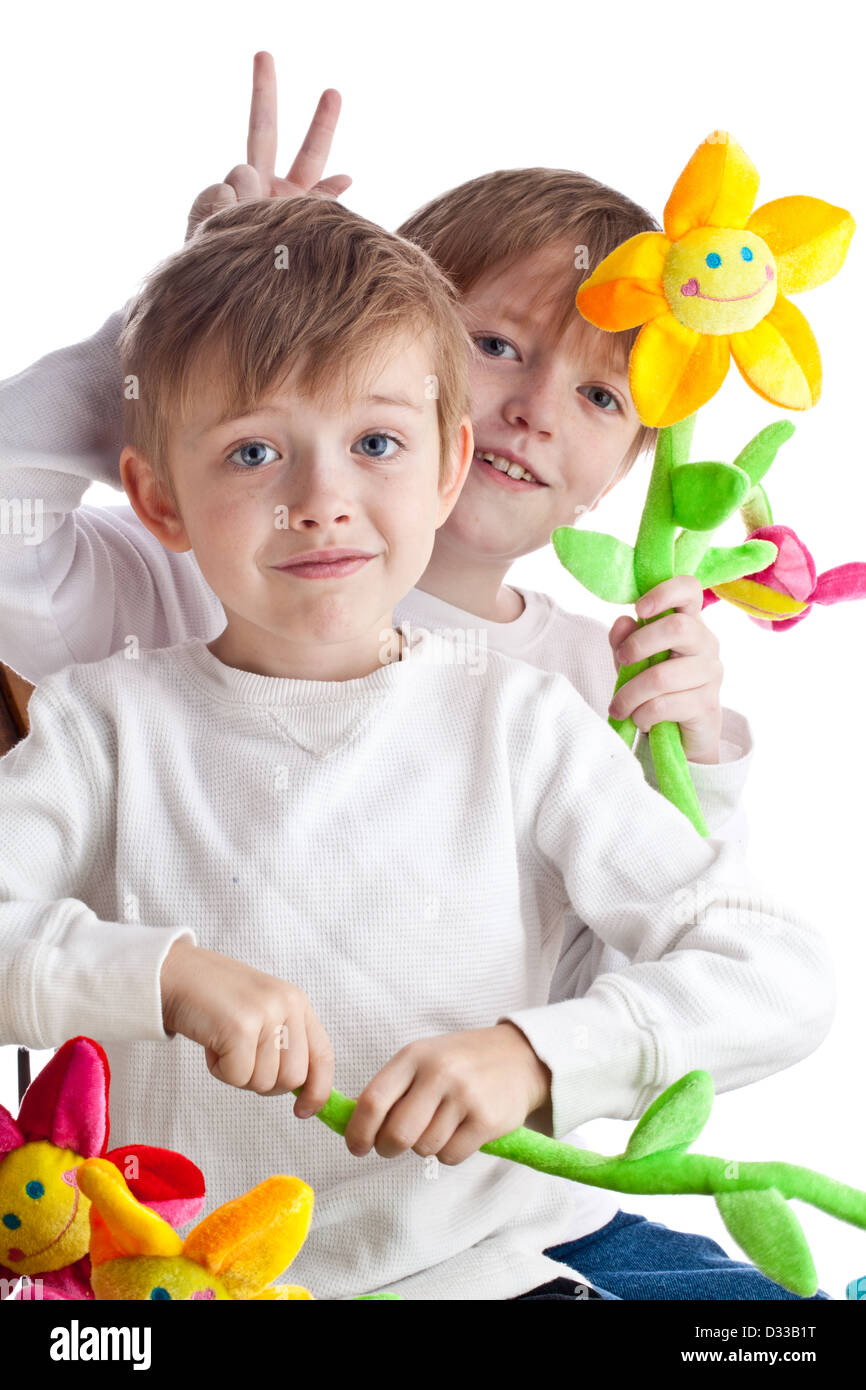 Deux frères blonds avec des fleurs souriant jouet Banque D'Images