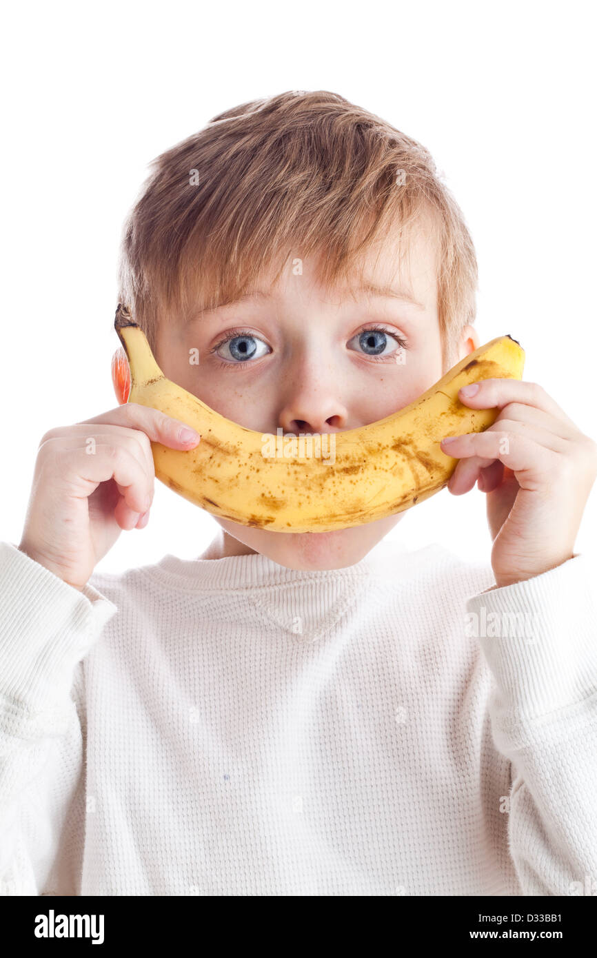 Garçon aux yeux lumineux tient à la banane apparaissent comme un sourire sur son visage Banque D'Images