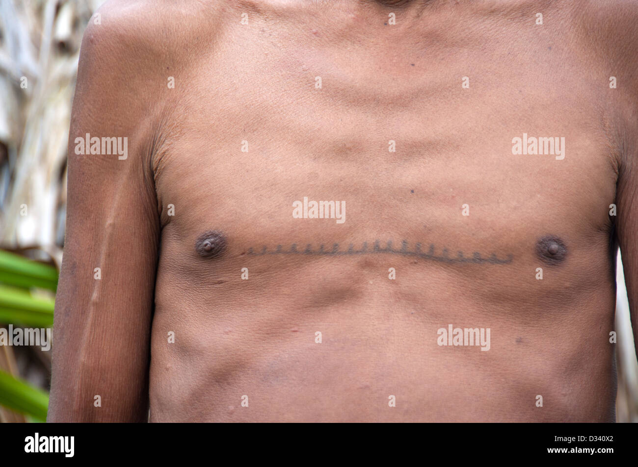 Un Matses Mayorunas homme âgé avec des tatouages traditionnels en face d'une maloca (maison traditionnelle), l'Amazonie péruvienne Banque D'Images