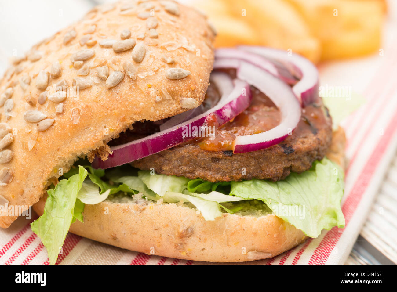 Veggie burger avec un oignon rouge, laitue, et savourez un petit pain pain servi avec un côté de frites - faible profondeur de champ Banque D'Images