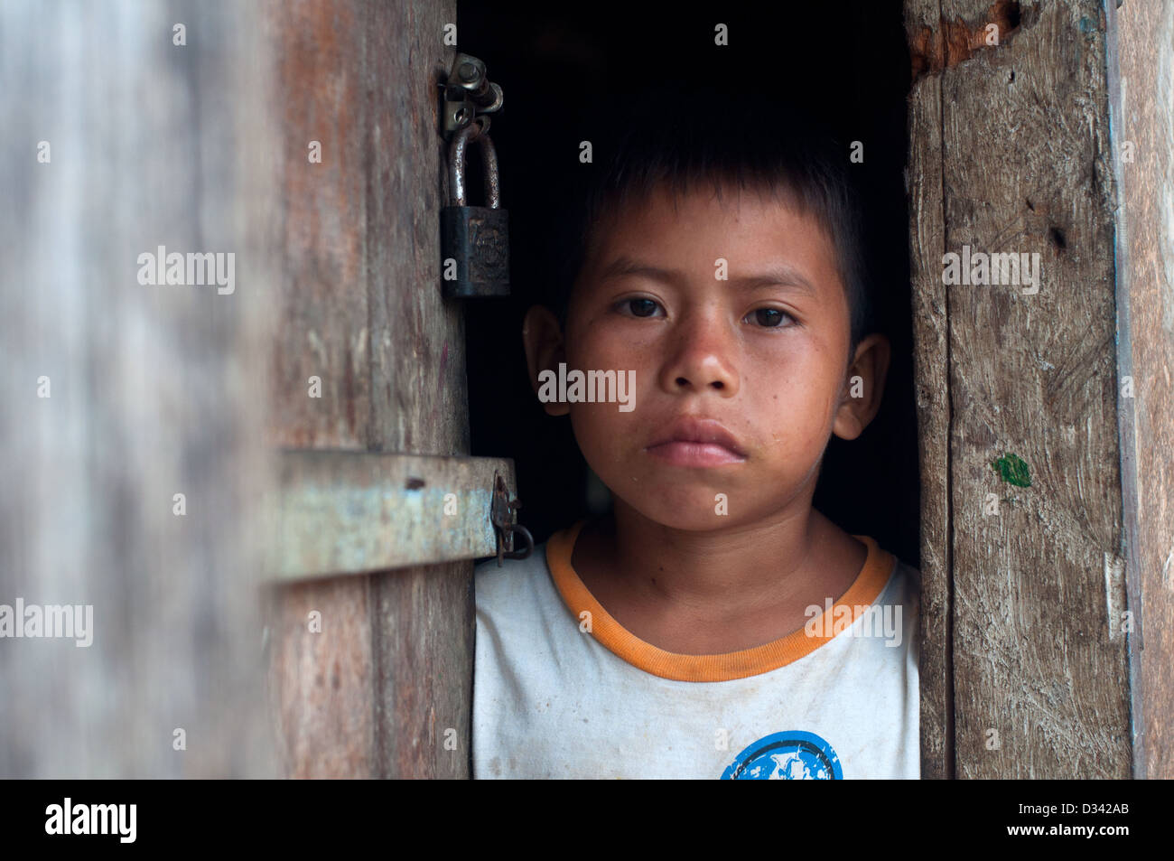 Un jeune garçon Mayorunas Matses sur le seuil de sa maison en bois, Colonia Angamos, l'Amazonie péruvienne Banque D'Images