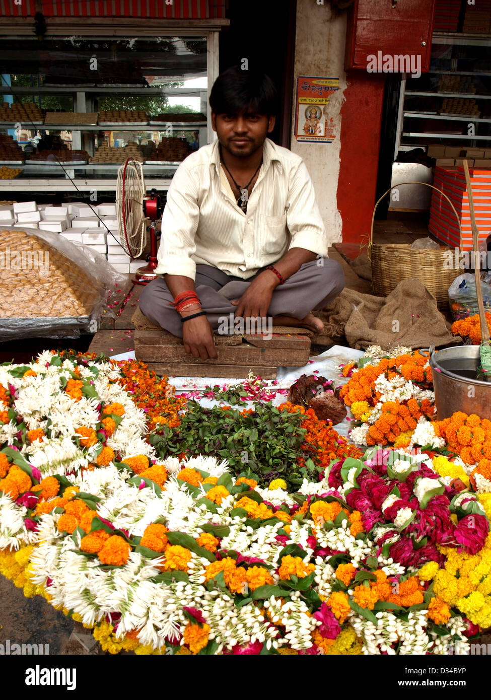 Man selling puja offrant des guirlandes de fleurs à l'extérieur de temple à Varanasi, Inde. Banque D'Images